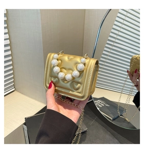Detail of mini gold PU leather bag with heart quilting and pearl beaded handle