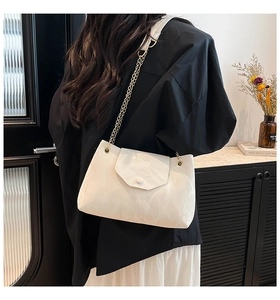 Detail der cremeweißen Tasche mit glänzender Wolkentextur und goldener Kette am Model