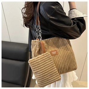 Detail of khaki corduroy tote and matching pouch with leather chain strap on model