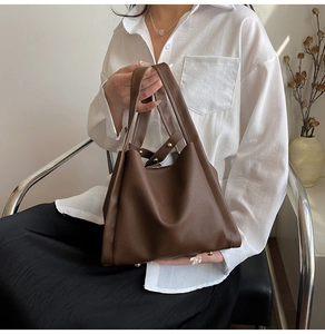 Detail view of dark brown lychee texture leather bucket bag with gold rivets on strap