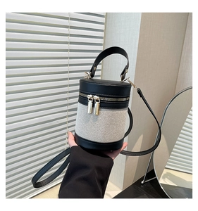 Close-up of contrast cylinder bucket bag featuring black leather and woven canvas details