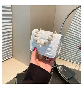 Detail of white heart-quilted handbag with luxury pearl handle and gold chain strap