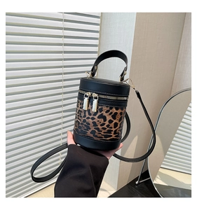 Close-up of leopard print cylinder bag with dual zippers and black leather stitching detail