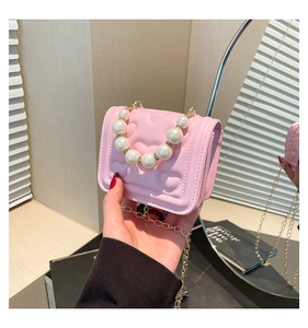 Detail of pink heart quilted mini bag featuring elegant pearl handle and gold chain