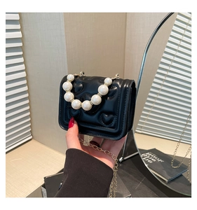 Detail of black mini crossbody bag with heart quilting and elegant pearl handle