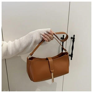 Close-up of caramel brown PU leather shoulder bag with elegant gold metal pendant detail