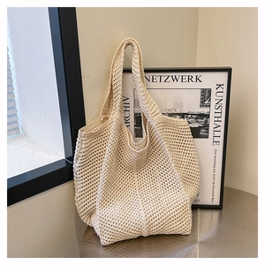Gros plan du sac cabas en maille beige avec texture ajourée complexe sur une table