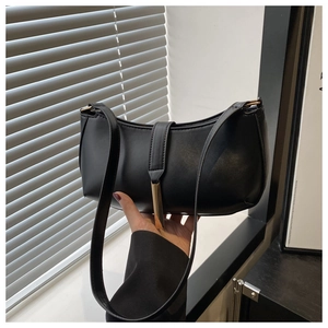 Detail of minimalist black PU leather baguette bag with a sleek gold metal buckle