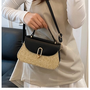 Detail of woven straw crossbody bag with black leather flap and gold oval metal clasp