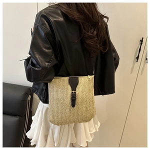 Straw crossbody bag with black leather strap detail worn by model in casual style
