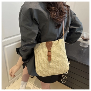 Detail showing natural straw weaving texture and brown leather strap on crossbody bag