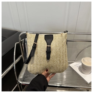 Detail of beige straw crossbody bag with herringbone weave and black leather buckle strap