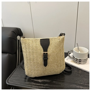 Detalle de bolso de paja tejida con correa de cuero sintético negro y hebilla dorada fina