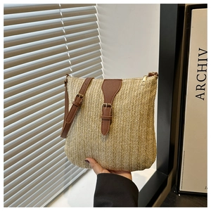 Detail of hand-woven straw crossbody bag with brown leather strap and fine herringbone texture