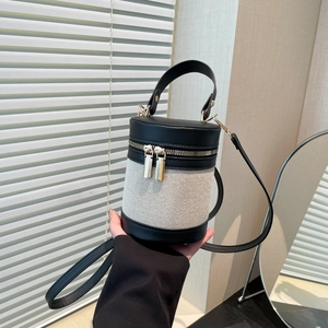 Minimalist cylinder bucket bag in black leather and beige canvas contrast with gold zippers