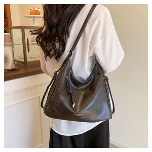 Detailed view of the dark brown leather shoulder bag with side tassel and printed logo