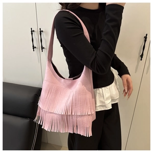 Detail of pink hobo bag with long tassels and litchi grain faux leather texture