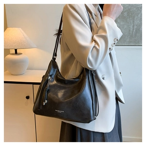 Macro detail of high-quality black leather hobo bag with silver brand logo and side zippers