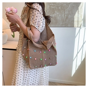 Detail of woven tote bag with colorful beads and hollow crochet texture worn by model