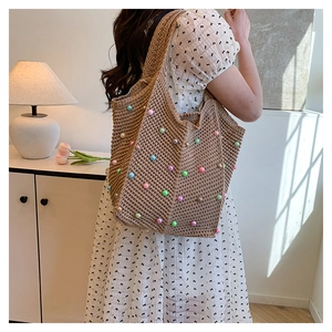 Detail of hand-woven tote bag with colorful pearls shown on model's shoulder