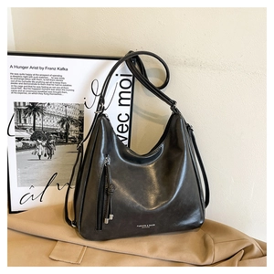 Detail of dark grey retro PU leather bag with vertical zipper and tassel on trench coat