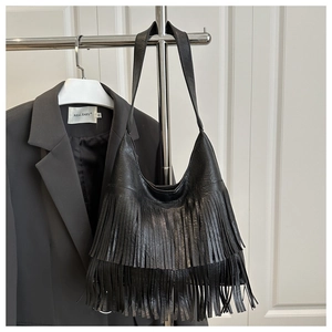 Détail d'un sac hobo en cuir noir à franges étagées sur un cintre métallique