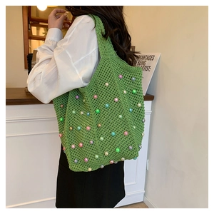 Close-up of green crochet tote bag with colorful beads worn over the shoulder