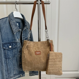 Brown corduroy tote bag with chain strap and matching pouch hung on a hanger