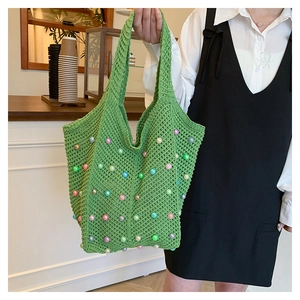 Close-up of green crochet tote bag with colorful pearls and hollow knit texture