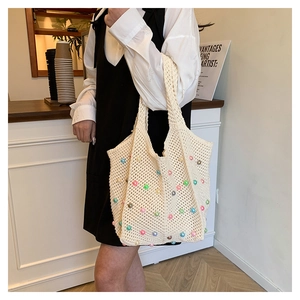 Detail of hand-woven beige crochet tote bag with colorful pearl accents on hollow pattern