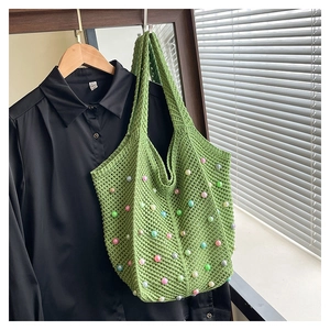Detail of green crochet tote bag with colorful beads and hollow knit texture on a shoulder strap