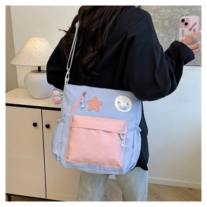 Detail der blauen Segeltuch-Umhängetasche mit rosa Tasche und süßem Stern-Patch