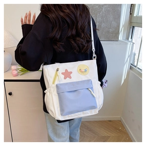 Detail of canvas school bag featuring pink star patch and side elastic pocket