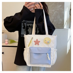 Detail of a white canvas tote bag featuring light blue pockets and star badge accents