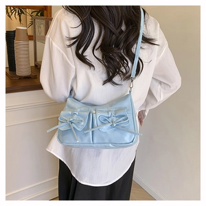 Détail du sac à main en cuir verni bleu clair avec nœuds et deux poches avant