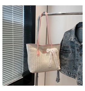 Detail of contrast straw tote with pink leather strap and lace bow accent