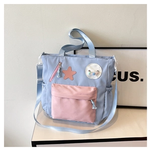 Detail of light blue nylon tote bag with pink star patch and adjustable strap