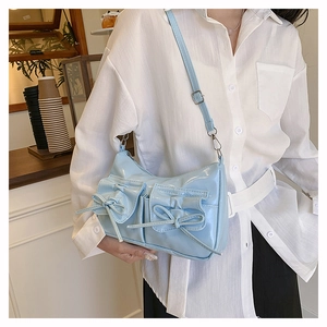 Détail du sac bandoulière bleu clair avec poches à nœuds et finition cuir brillant