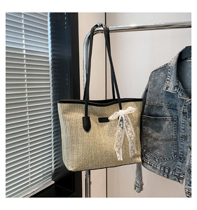 Close-up of beige woven tote bag showing ripple texture, black straps and lace bow detail