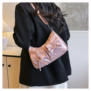 Sac à bandoulière rose avec nœuds et doubles poches porté sur un blazer noir élégant