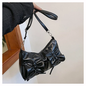 Détail d'un sac à main noir brillant avec boucles argentées et deux poches à nœuds avant