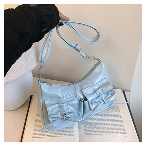 Vue détaillée du sac en cuir verni bleu clair avec nœuds sur un livre vintage