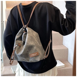 Detailed back view of a gray vintage canvas backpack with brown leather straps on a model