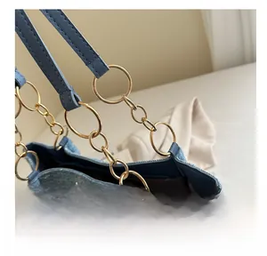 Détails des maillons de chaîne en métal doré sur un sac à main en denim bleu et strass