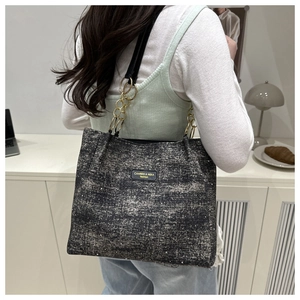 Détail du sac cabas gris anthracite scintillant avec chaîne dorée sur un mannequin