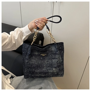 Détail du sac cabas en denim avec poignée en chaîne dorée et motif à pois blancs