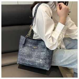 Détail du cabas en denim bleu foncé avec des strass brillants et une chaîne dorée