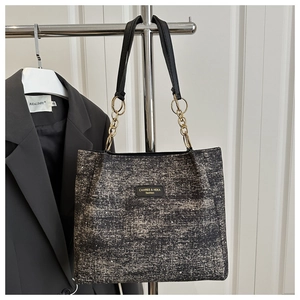Détail d'un cabas en tweed avec chaîne dorée et poignées en cuir noir de luxe