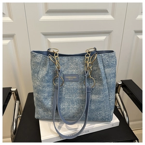 Détail du sac cabas en denim bleu avec strass et bandoulière en chaîne dorée
