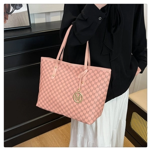 Detail of pink monogram tote bag featuring golden M-logo pendant and metallic rivets
